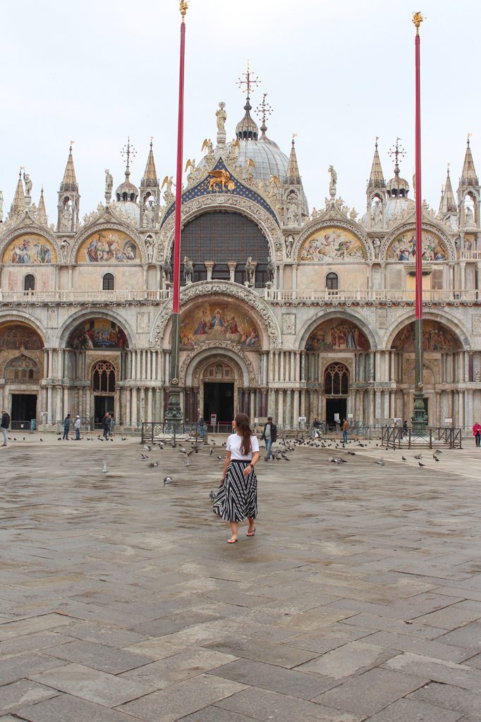 girl walking in an empty piazza san marco in front of saint marks basilica