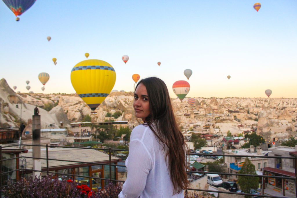 girl standing on a balcony with hot air balloons in background