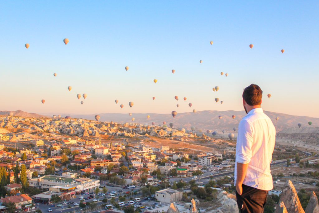 guy standing on lovers hill overlooking flying balloons